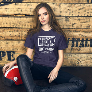 A woman wearing a heather midnight blue color short sleeved t-shirt. The t-shirt features hand drawn lettering in white with the words "Our creativity is an outflow of His."