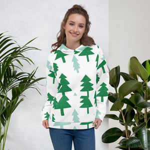 A woman wearing a white hoodie with illustrated pine trees all over the fabric including the hood. The pine trees colors are in light and dark green.