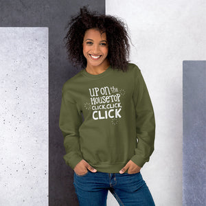 A woman wearing an olive green sweatshirt featuring hand drawn lettering with the words "Up on the housetop, click, click, click" in white. There are three white stars around the words. 