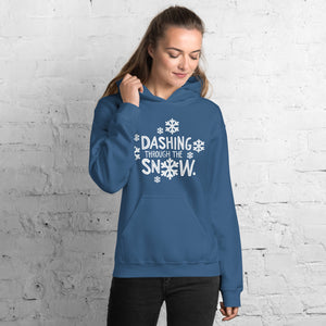 A woman wearing a blue hoodie featuring hand drawn lettering in white reading Dashing through the snow. There are white snowflakes around the words. 