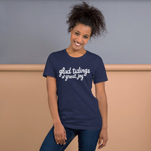 Load image into Gallery viewer, A woman wearing a navy blue short sleeved t-shirt. The tee features lettering of the words &quot;glad tidings of great joy.&quot; The words are in white. 