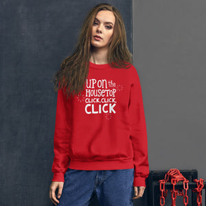 A woman wearing a red sweatshirt featuring hand drawn lettering with the words "Up on the housetop, click, click, click" in white. There are three white stars around the words. 