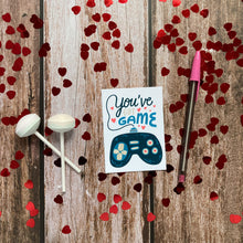 Load image into Gallery viewer, An image of a single classroom Valentine with heart confetti and Valentine’s sweets around it. The design features the words “You’ve got game” with an illustrated gaming controller. 